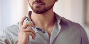 Homem de camisa social passando perfume