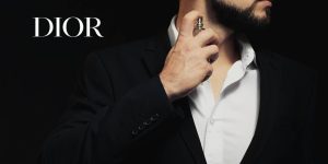 Homem de terno preto passando perfume; ao seu lado, uma logo da Dior