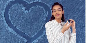 Mulher jovem passando perfume; ao fundo, uma foto de um coração desenhado em uma superfície congelada