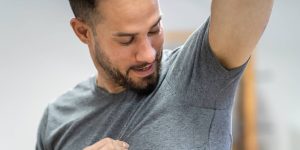 Homem olhando satisfeito para as próprias axilas, que estão secas